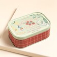 A vibrantly illustrated sardine tin-inspired candle