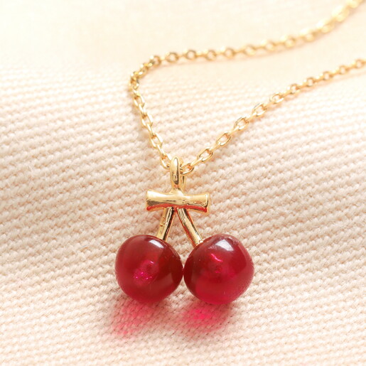 Beaded Cherry Pendant Necklace in Gold on a neutral background