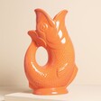 A medium-sized glazed ceramic gurgle jug in orange