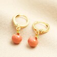 Enamel Peach Huggie Hoop Earrings in Gold on a neutral background