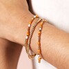 Close Up Model Shot of Set of 3 Stainless Steel Orange Layered Beaded Bracelets in Gold