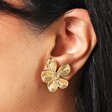 Close Up of Stainless Steel Large Asymmetric Flower Stud Earrings in Gold on Model