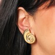 Close Up of Stainless Steel Large Swirl Shell Stud Earrings in Gold on Model