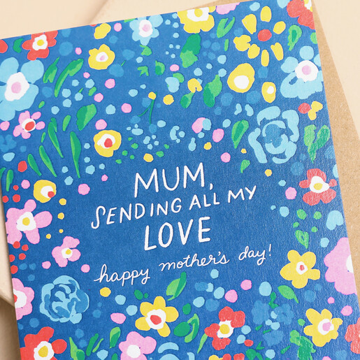 Close up of Ohh Deer Sending All My Love Mother's Day Card with white text, florals and blue background. With a brown envelope on a neutral background