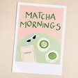 The print features a Polaroid-style image with a soft pink backdrop and green handwritten text that reads 'Matcha Mornings.' 