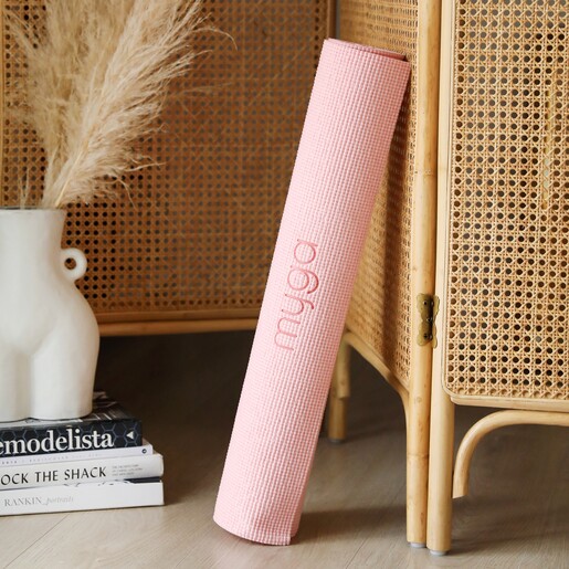 Pink Yoga Mat rolled up leaning on the side of a cupboard