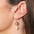 Close Up of Cloisonne Ball and Pearl Drop Earrings in Gold on Model