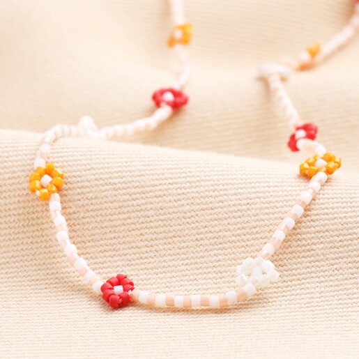 Close Up Red and Orange Daisy Beaded Necklace on a neutral background