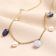 Semi Precious Blue Bead and Pearl Charm Necklace in Gold on a neutral background