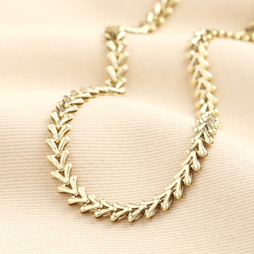 Stainless Steel Chevron Chain in Gold on a Beige Background A waterproof stainless steel chain necklace