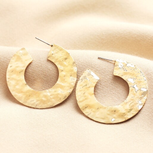 Oversized Hammered Flat Hoop Earrings in Gold on neutral background
