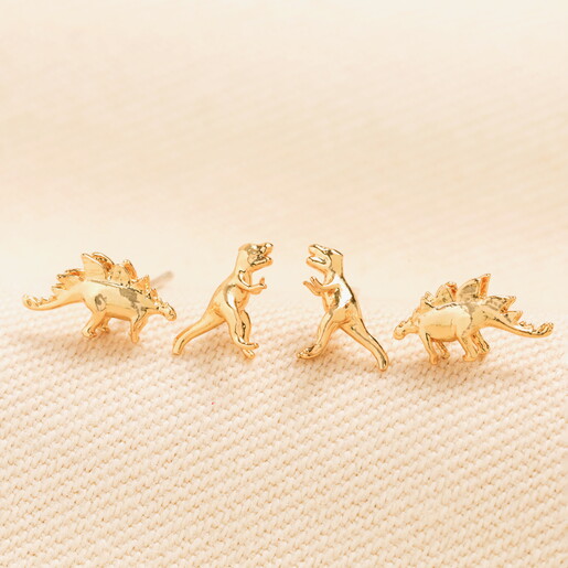 dinosaur stud earrings against pale pink background