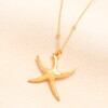 starfish pendant in gold against a pale pink background