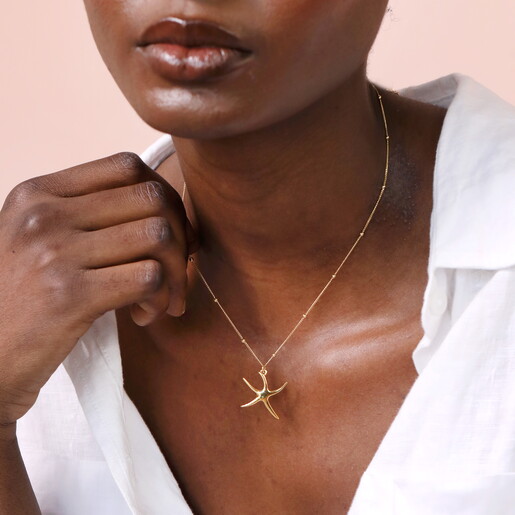 starfish pendant in gold against a pale pink background