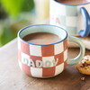 A Cream and Orange Checkerboard Print Ceramic Mug with a Green Handle and Daddy Wording