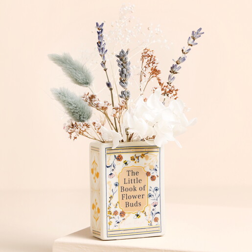 A Small Ceramic Vase in Cream with Gold Wording and Floral Cover Shaped Like a Book Filled with Dried Flowers