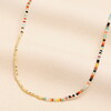 rainbow necklace against pale pink background