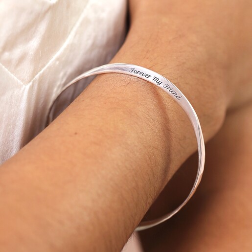 Personalised Hammered Sterling Silver Twisted Bangle against neutral coloured fabric