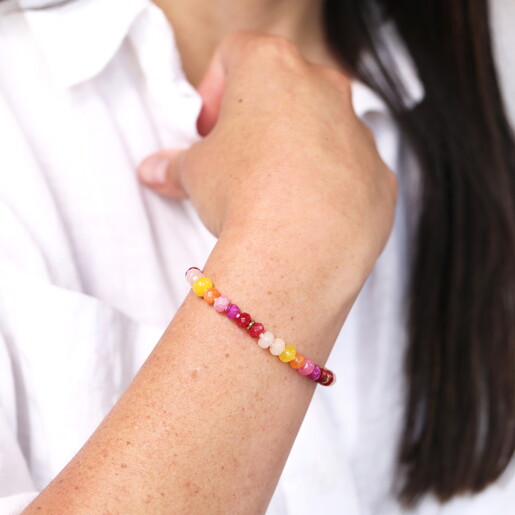 A Pink Red Purple Yellow and Orange Beaded Bracelet with Gold Spacers On Model