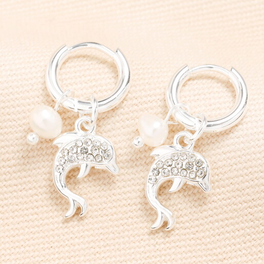 dolphin hoop earrings in silver against pale pink background