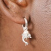 dolphin hoop earrings in silver against pale pink background