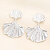 nature inspired earrings against a pale pink background