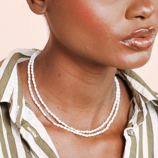 A Layered White Beaded Necklace With Silver Fish Shaped Beads