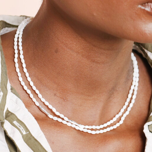A Layered White Beaded Necklace With Silver Fish Shaped Beads