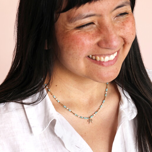 green and gold stainless steel bow charm necklace on model