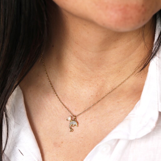 pearl and dolphin pendant necklace in gold close up on model