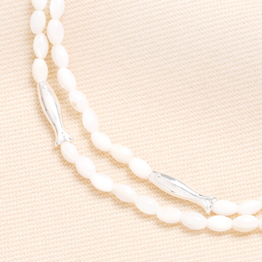 A Close Up of Silver Fish Shaped Beads on White Beaded Layered Necklace