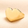 heart ring in gold against pale pink background