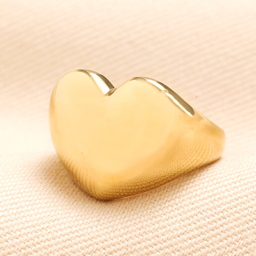 heart ring in gold against pale pink background