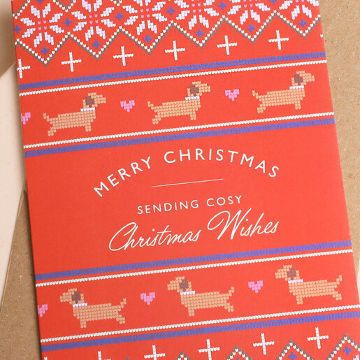 Close-up of Fair Isle knit pattern and dachshund illustration on festive red Christmas card