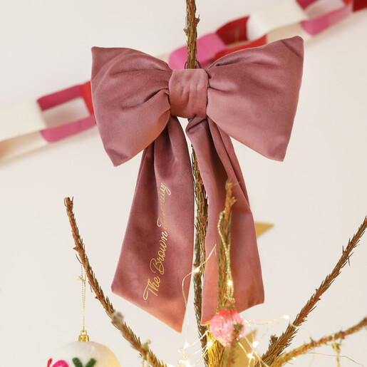 Personalised dusky pink velvet bow tree topper on the top branch of a Christmas tree