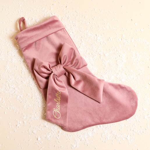 Personalised pink velvet Christmas stocking with a large bow and gold script name