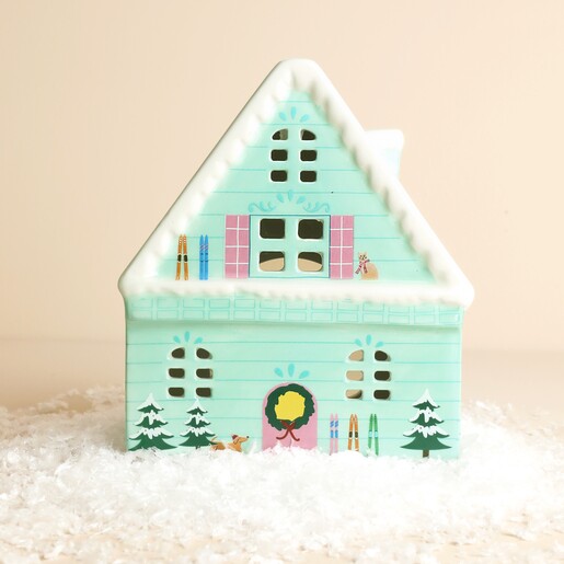 Front view of mint green ceramic ski chalet tealight holder on faux snow
