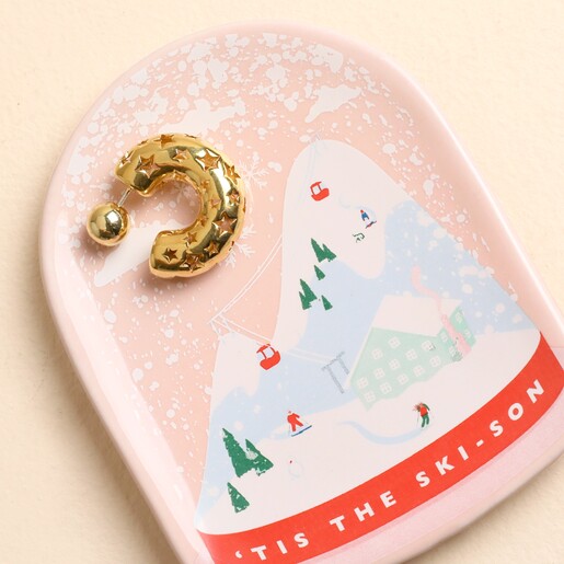 Snow globe shaped ceramic ski scene trinket dish holding a gold earring