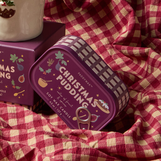 Angled view of the closed Christmas pudding bistro tin candle on red gingham.