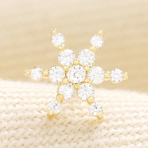 Close-up of a single gold snowflake stud earring with cubic zirconia crystals