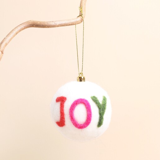 White felt Christmas bauble hanging from a branch with colourful JOY lettering.