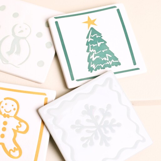 Close-up of four festive ceramic coasters with holiday designs