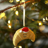 Ceramic croissant Christmas ornament with Santa hat hanging on a Christmas tree