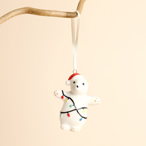 Ceramic polar bear hanging decoration with Santa hat and fairy lights on branch