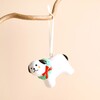 Ceramic Christmas dog hanging decoration with wreath collar suspended by a white ribbon