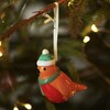 Ceramic robin decoration hanging on a Christmas tree branch with fairy lights