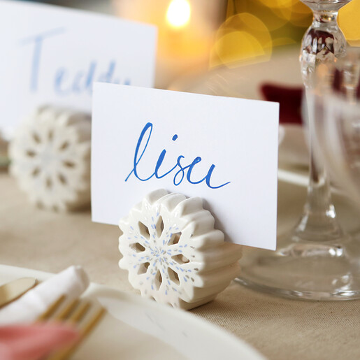 White ceramic snowflake holder displaying a handwritten name place card on dining table