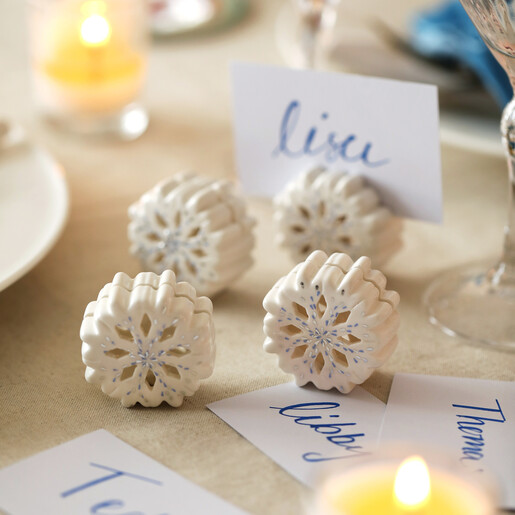 Set of four white ceramic snowflake place card holders on festive dinner table