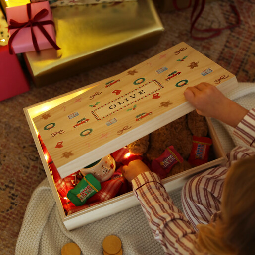 Child opening a personalised wooden Christmas Eve box with festive motifs