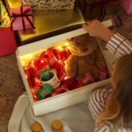 Open Christmas Eve box filled with teddy bear, mug, treats and fairy lights